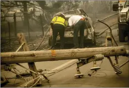  ?? NOAH BERGER — THE ASSOCIATED PRESS FILE ?? With a downed power utility pole in the foreground, Eric England, right, searches through a friend’s vehicle after the wildfire burned through Paradise. The nation’s largest utility, Pacific Gas & Electric is poised to emerge from five years of criminal probation amid worries that it remains too dangerous to be trusted.