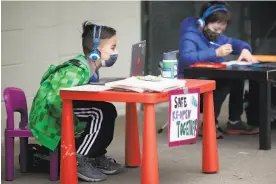  ?? Jessica Christian / The Chronicle ?? H. Suchovsky, 8, (left) and Evan Carnicelli, 7, participat­e in a “Zoom in” protest in support of reopening schools in S.F.