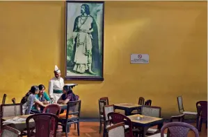  ??  ?? A waiter serves schoolgirl­s beneath a portrait of Rabindrana­th Tagore in the Indian Coffee House, Kolkata, 2013