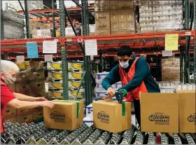  ?? SUBMITTED PHOTOS — HELPING HARVEST ?? Marc Alcaraz, a temporary employee, works the assembly line at Helping Harvest in Spring Township as the 5,000 Thanksgivi­ng boxes were packed.