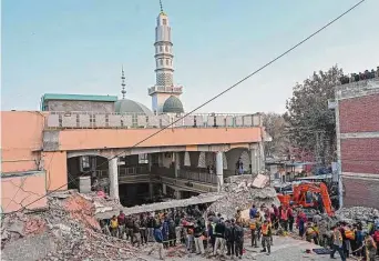  ?? Abdul Majeed / AFP/Getty Images ?? Security personnel and rescue workers prepare to search for the blast victims in the debris of a damaged mosque inside the police headquarte­rs in Peshawar on Monday.