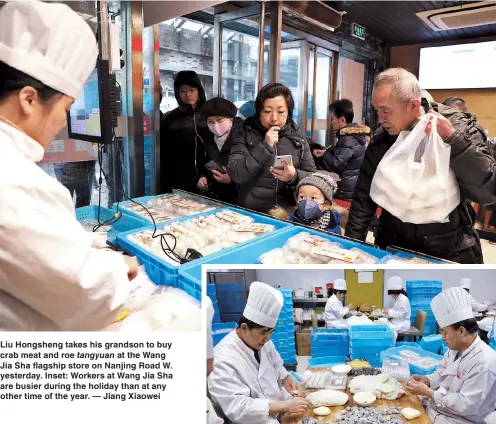  ??  ?? Liu Hongsheng takes his grandson to buy crab meat and roe tangyuan at the Wang Jia Sha flagship store on Nanjing Road W. yesterday. Inset: Workers at Wang Jia Sha are busier during the holiday than at any other time of the year. — Jiang Xiaowei
