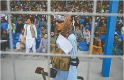 ??  ?? A Taliban fighter keeps vigil as spectators watch the Twenty20 cricket match being played between two Afghan teams.