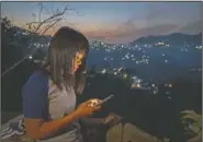  ??  ?? A police officer who fled Myanmar following a military coup looks at her phone trying to connect to families she was forced to leave behind. At night, all of the officers go to sleep on mattresses laid on the floor of a single room.