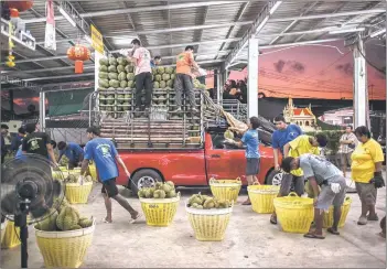  ?? — AFP photos ?? Workers stack durians on a truck at the durian suppliers Paeng Jae Ting at Noen Sung wholesale fruit market.