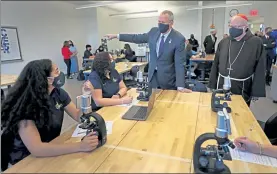  ?? POOL PHOTOS ?? Gov. Charlie Baker, left, and Cardinal Sean O’Malley tour St. Mary’s Catholic school in Lynn on Friday, pausing to talk with students in a science lab.