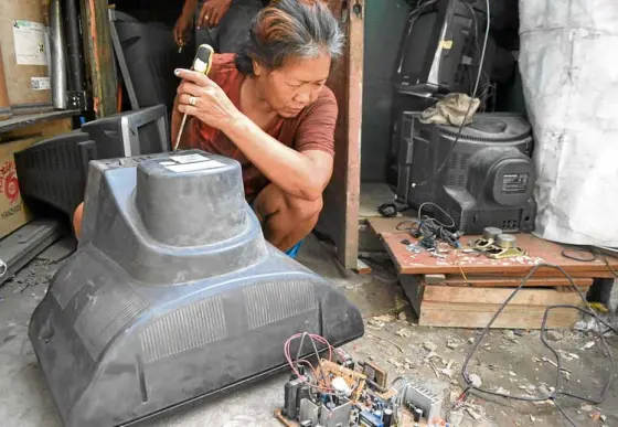  ?? —KRISTINE ANGELI SABILLO/INQUIRER.NET ?? RESTORE ORDESTROY Awoman opens up an old television set to check if it can still be repaired and sold. If it is beyond repair, they will have to dismantle it and break its glass to get the copper wires and other valuable metals.