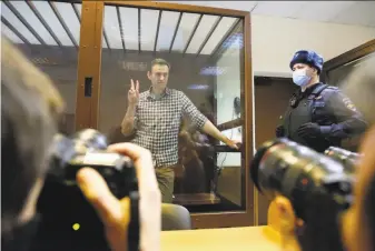  ?? Alexander Zemlianich­enko / Associated Press ?? Russian opposition leader Alexei Navalny stands in a cell during a court hearing in Moscow. Navalny’s arrest and imprisonme­nt have fueled a huge wave of protests across Russia.