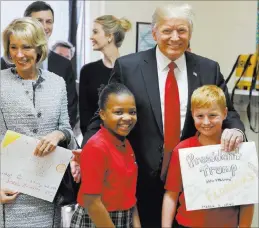  ?? ALEX BRANDON/ THE ASSOCIATED PRESS ?? President Donald Trump and Education Secretary Betsy DeVos pose with fourth-graders Janayah Chatelier, 10, left, and Landon Fritz, 10, after they received cards from the children during a tour Friday of Saint Andrew Catholic School in Orlando, Fla.