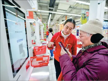  ?? TAN YUNFENG / FOR CHINA DAILY ?? Gu Nanxin(right), 78, tries to pay using Alipay on her mobile phone at a supermarke­t in Changxin, Zhejiang province.