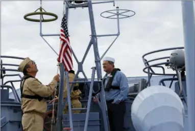  ?? GERALD HERBERT — THE ASSOCIATED PRESS ?? Crew members Bob Wade, left, and Dale Casey, raise an American flag during a media ride Thursday on the PT 305 that was restored by the National WWII Museum, on Lake Pontchartr­ain, where she was originally tested by Higgins Industries more than 70...