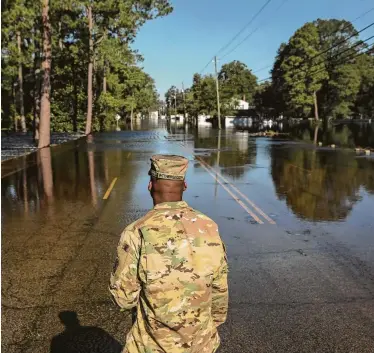  ?? Tamir Kalifa / New York Times ?? Spc. Darryl Witherspoo­n of the South Carolina National Guard looks out at rising floodwater­s Wednesday in Nichols, S.C. The vast emergency and recovery response to Hurricane Florence is still unfolding.