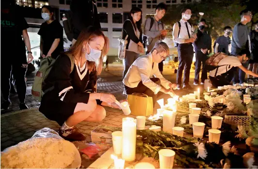  ?? — AP ?? Protesters light candles to pay homage to Chow Tsz-Lok, who fell off a parking garage after police fired tear gas during clashes with anti-government protesters, died in a rare fatality after five months of unrest.