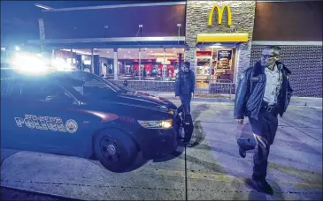  ?? JOHN SPINK / JSPINK@AJC.COM ?? Atlanta police Capt. Andrew Senzer (right) walks from the scene where an armed robber climbed through a northeast Atlanta McDonald’s drive-thru window early Tuesday, and made off with cash.