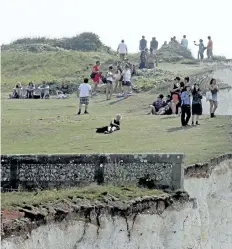  ?? GARETH FULLER/THE ASSOCIATED PRESS ?? People stroll on the cliffs at Birling Gap in England on Monday. More than 130 people have been treated for running eyes, sore throats and breathing problems after a chemical haze spread over a stretch of southern England coastline.