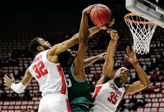  ?? Photos by Stacy Revere / Getty Images ?? UH’s Reggie Chaney, left, and teammate Fabian White Jr. block a shot by Cleveland State Deante Johnson. White sparked a 9-0 run in the first half.