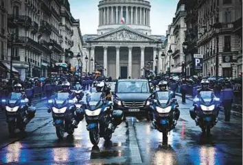  ?? AFP ?? ■ French gendarmes escort the coffin of the late Lieutenant Colonel Arnaud Beltrame during a funeral procession leaving the Pantheon (background) as part of a national tribute in Paris.