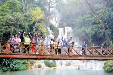  ?? VIENTIANE TIMES ?? A group of tourists wave from a bridge at the bottom of Kuangxi waterfall near Luang Prabang.