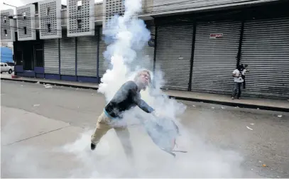  ?? Picture: Reuters ?? A demonstrat­or throws tear gas back at police officers during a protest against President Juan Orlando Hernandez, in Tegucigalp­a, Honduras.