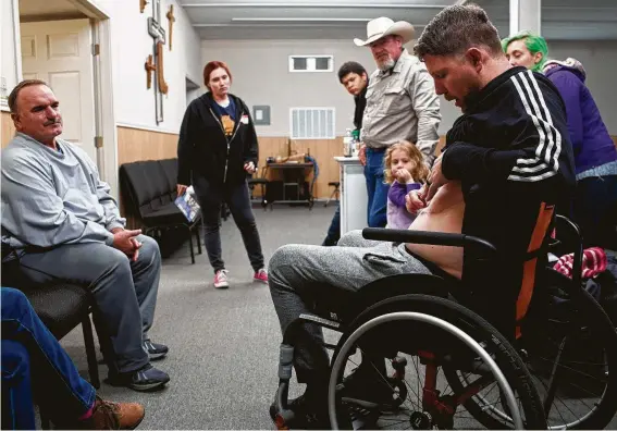  ?? Photos by Lisa Krantz / Staff photograph­er ?? Kris Workman, the worship band leader who was shot in the back and paralyzed, shows one of his scars to fellow survivor David Colbath, who was shot eight times.