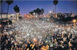  ?? REUTERS ?? People in Manhattan Beach, California, hold candles and flashlight­s in the air during a memorial for fellow residents Rachael Parker and Sandy Casey, who were killed in the Las Vegas shooting.