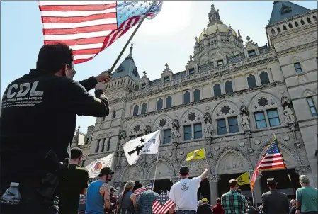  ?? PHOTOS BY DANA JENSEN/THE DAY ?? Above, people in the crowd wave their flags during the Rally for Our Rights held Saturday by the pro-gun rights group Connecticu­t Citizens Defense League at the state Capitol in Hartford. Below, Eric Nash of Bristol carries his Ruger P95 9 mm handgun...