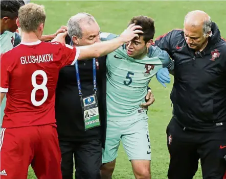  ??  ?? He can’t carry on: Portugal’s Raphael Guerreiro (second from right) is helped off the pitch after suffering an injury.