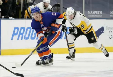  ?? Associated Press photos ?? Islanders center Mathew Barzal skates with the puck ahead of Penguins center Jared McCann in the second period.