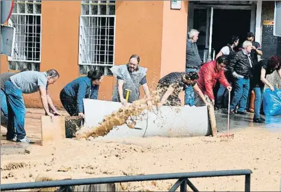  ?? VÍCTOR LERENA / EFE ?? Varios vecinos bloquean el paso del agua en la zona de Arganda del Rey, en la Comunidad de Madrid