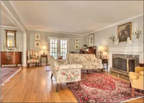  ??  ?? The L-shaped dining and living rooms flood with natural light and open to the back deck and porch through French doors.