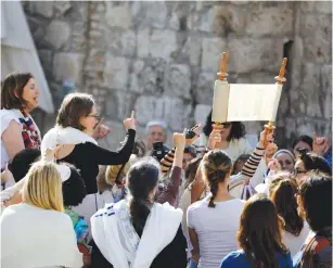  ?? (Ronen Zvulun/Reuters) ?? WOMEN OF THE Wall members pray with a Torah scroll near the Western Wall on July 24, the first day of the Hebrew month of Av.