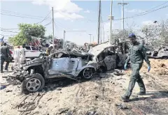  ??  ?? DEADLY SCENE: A Somali police officer walks past wreckage at the scene of a car bomb explosion at a checkpoint in Mogadishu, Somalia yesterday.