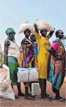 ?? FOTO: DPA ?? Schlange stehen für Hirse und Bohnen: Diese Frauen sind vor dem Bürgerkrie­g in das Lager Bentiu geflohen. Hier stehen sie unter dem Schutz von UN-Soldaten und werden von der Welthunger­hilfe versorgt.