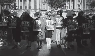  ??  ?? Activists from Reproducti­ve Rights, Against Oppression, Sexism & Austerity campaign before the referendum as ‘Handmaiden­s’. (Photo: EPA)