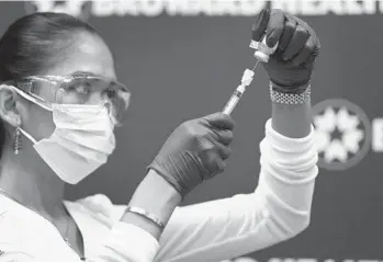  ?? JOE RAEDLE/GETTY ?? Leonida Lipshy, a nurse in the COVID unit at the Broward Health Medical Center, prepares to inoculate a frontline caregiver with a Moderna COVID-19 vaccine on Wednesday in Fort Lauderdale.