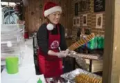  ?? ANNE-MARIE JACKSON/TORONTO STAR ?? Co-owner Cindy Jun dusts cinnamon sugar on a signature Tornado Potato at the family’s stall at the Toronto Christmas Market in the Distillery District.