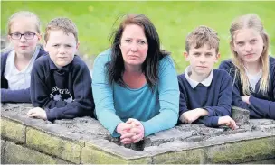  ??  ?? ●●Assistant head Liza Ferdinand with pupils Olivia Clapperton, 11, Sam Collins, six, Joshua Clapperton, eight and Lucy Ferdinand, 10, with the remains of the school wall