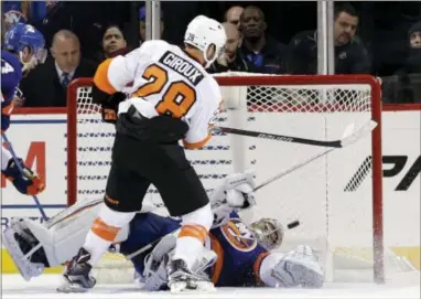  ?? SETH WENIG — THE ASSOCIATED PRESS ?? Claude Giroux, left, puts the winning goal past Islanders goalie Thomas Greiss in overtime Sunday, giving the Flyers a much-needed 3-2 victory. It was Giroux’s first goal since Dec. 21.