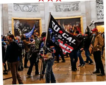  ??  ?? Invaded: Flag-waving protesters roam under the Capitol Rotunda