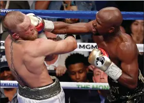  ?? AP PHOTO/ERIC JAMISON ?? Floyd Mayweather Jr. hits Conor McGregor in a super welterweig­ht boxing match Saturday at T-Mobile Arena in Las Vegas.