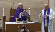  ?? MORNING SUN FILE PHOTO ?? Reverend Loren Kowalinski, of Sacred Heart Parish, prepares for communion during the parish’s Sunday Mass, streamed over Youtube. Standing to the side is Fr. Don Henkes, a senior priest at Sacred Heart.