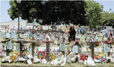  ?? /Reuters ?? Grave situation: Lesley Mendonca, of Houston, visits the memorial for victims of the Robb Elementary School shooting, at Uvalde Town Square in Texas. Regular mass shootings in the US have spurred demand for insurance policies against such incidents.