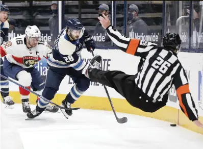  ?? JAY LAPRETE AP ?? Florida’s Aleksander Barkov and Columbus’ Oliver Bjorkstran­d chase a puck under falling referee Jake Brenk during the second period Tuesday in Columbus, Ohio.