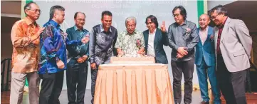  ??  ?? Masing (centre) cuts the celebratio­n cake as others look on.