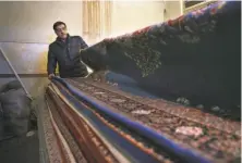  ?? Vahid Salemi / Associated Press ?? Mahmoud Morshedi displays rugs at his shop in Kashan. A small rug can take up to four years to make and cost $6,000.