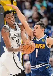  ?? David Zalubowski / Associated Press ?? Brooklyn’s Nic Claxton, left, pulls in a rebound as Denver’s Michael Porter Jr. defends in the Nets’ 122-120 win in Denver on Sunday. Claxton had 20 points on 8-of-9 shooting.