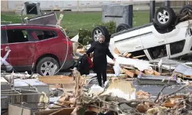  ?? Indiana. Photograph: Scott Olson/Getty Images ?? A woman walks through debris piled up outside a restaurant destroyed by a tornado on 15 March in Winchester,