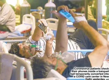  ?? AFP ?? Coronaviru­s patients check their phones inside a banquet hall temporaril­y converted into a COVID care center in New Delhi yesterday.