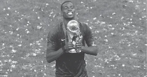  ?? THANASSIS STAVRAKIS/AP ?? Paul Pogba celebrates with the trophy following France’s 4-2 win over Croatia in Sunday’s World Cup final in Moscow. Pogba had the game-winning goal.