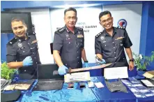  ??  ?? Habibi (centre) and other police officers with the weapons that were seized from the suspects.